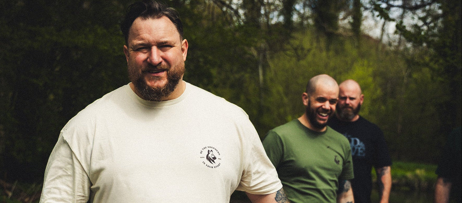 Three men walking outdoors in a forested area